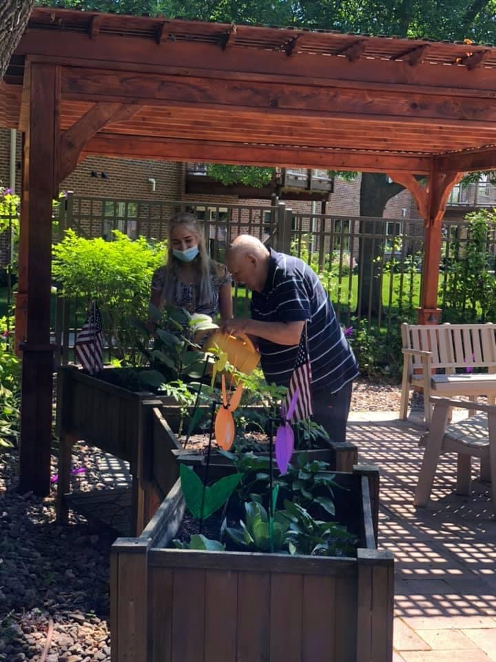 Xia Lowery supporting an older adult watering a garden